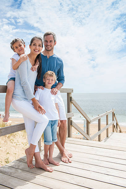 family standing on a wood pontoon deck by the sea happy family  standing on a wood pontoon in front of the sea in summertime two parents photos stock pictures, royalty-free photos & images