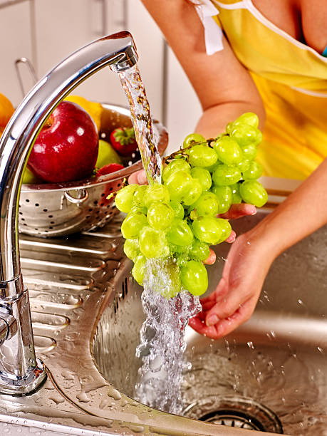 istock Woman washing fruit at kitchen 475530346
