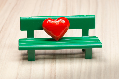 Red heart on green bench, love symbol