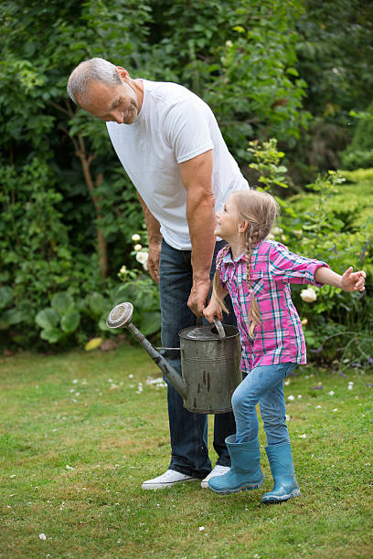 istock Father and daughter carrying watering can 475535870