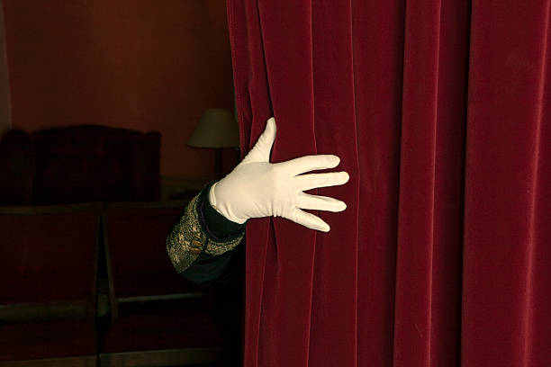 istock Hand in white gloves reveal a red curtain. 475537625