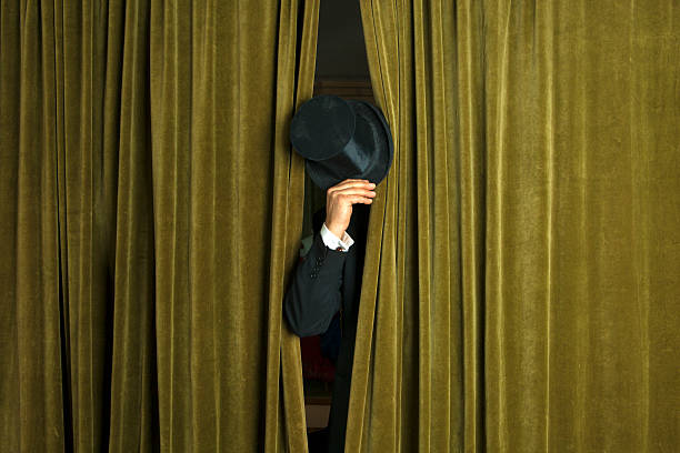 Actor with opera hat appears from behind the curtain. Theatre: Actor with opera hat appears from behind the curtain. classic curtains stock pictures, royalty-free photos & images