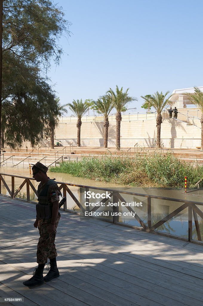 Jordanian and Israeli soldiers at Bethany-beyond-the Jordan Bethany-beyond-the-Jordan, Jordan - November 11, 2010: Bethany-beyond-the-Jordan is considered by scholars to be the most likely location of the baptism of Jesus. Inaccessible to tourists before the 1994 peace agreement between Jordan and Israel, it is now the only place on the Jordan River open to visitors. In the foreground is a Jordanian soldier; across the river are two Israeli soldiers. Adult Stock Photo