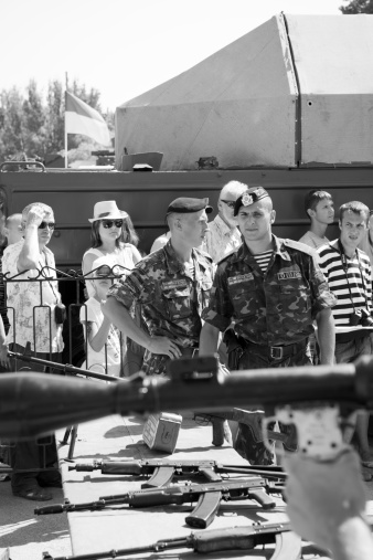 Sevastopol, Crimea, Ukraine - July 28, 2013: During the annual Navy Day event at the Black Sea port of Sevastopol, a Ukrainian sailor looks on as a civilian holds a rocket propelled grenade, one of several weapons attendees are invited to handle. Sevastopol, located in Ukraine, is home to both Russian and Ukrainian Navy ships.