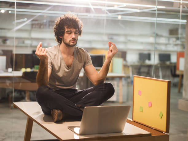 istock Creative young man meditating in the office. 475543024