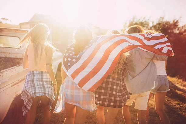 istock Teens walking with an American flag in sun flare 475543078