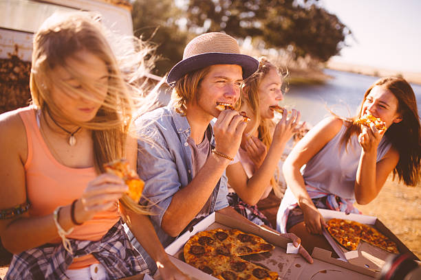 istock Friends sitting outside together eating takeaway pizza 475543172