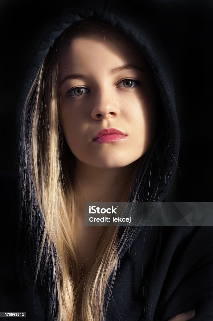 pensive young woman pensive young woman in black hood on black background Dark Stock Photo