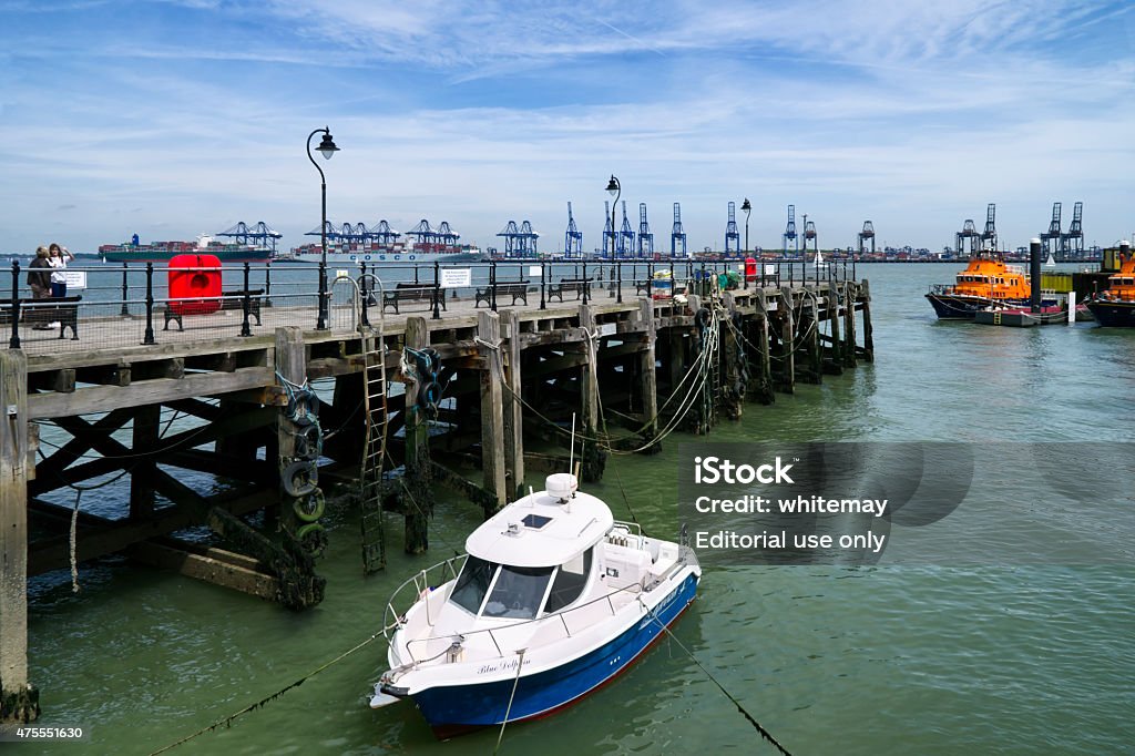 Halfpenny Pier at Harwich Harwich, Essex, England - May 11, 2015: Visitors to the Halfpenny Pier (also known as Ha’Penny Pier) at Harwich, Essex, England. Across the harbour are the cranes of Port of Felixstowe in Suffolk. Two lifeboats are moored nearby. 2015 Stock Photo