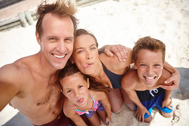 We'll always remember this vacation! A happy family taking a silly selfie at the beachhttp://195.154.178.81/DATA/i_collage/pu/shoots/804728.jpg male swimsuit standing arm around stock pictures, royalty-free photos & images