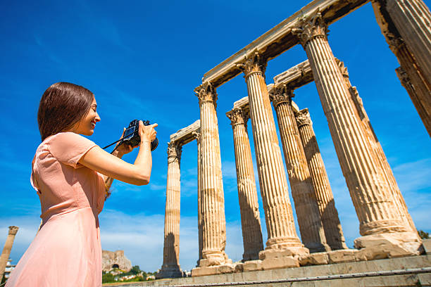 Young and smiling woman photographer taking picture with professional camera of Zeus temple in Acropolis