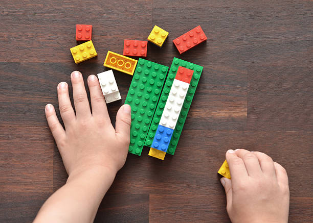 Playing with Lego Vancouver, B.C., Canada -- May 28, 2015:Closeup of a 5 year old boy playing with Lego building blocks on a wood table.  Lego is a popular toy brand that is available worldwide.   lego stock pictures, royalty-free photos & images