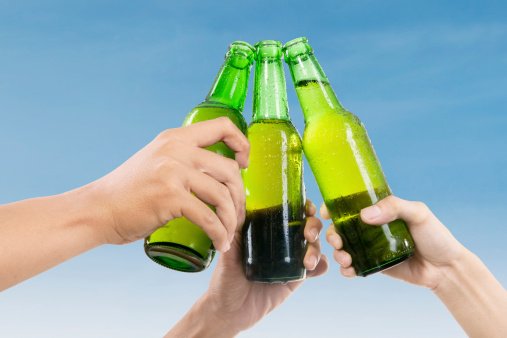 Closeup of hands toasting with bottles of beer
