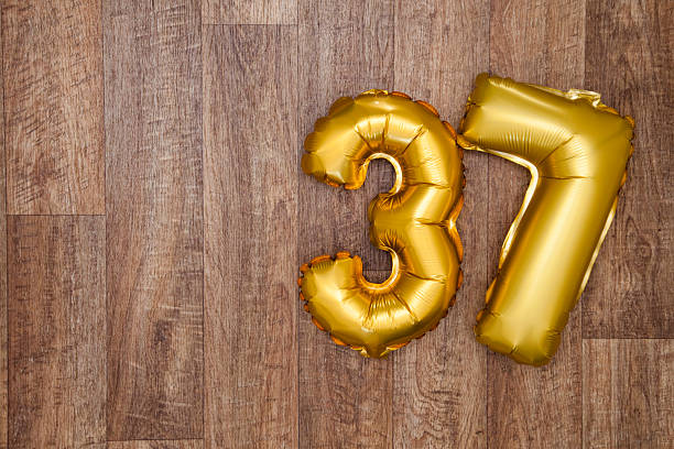 Gold number 37 balloon A gold foil number 37 balloon on a wooden background. The number is made from shiny golden foil and is inflated, it is on the right hand side of the image leaving copy space on the left of the image for your text or logo. number 37 stock pictures, royalty-free photos & images