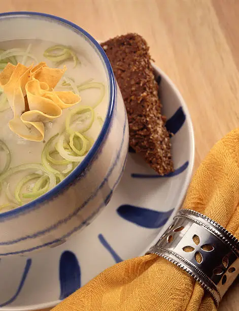 Decorated leek soup with rye bread  on a wooden table with a napkin with a silver napkin-ring