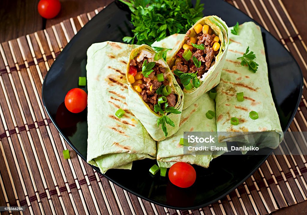 Burritos wraps with minced beef and vegetables Burritos wraps with minced beef and vegetables on a wooden background 2015 Stock Photo