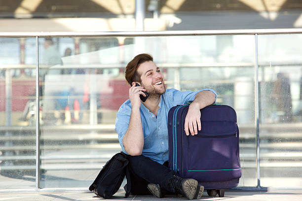 istock Man sitting with luggage and talking on mobile phone 475566770