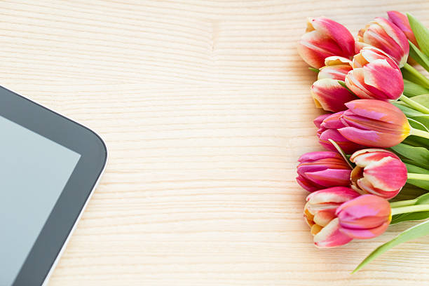 istock Spring Tulips and digital tablet on wooden background 475573319