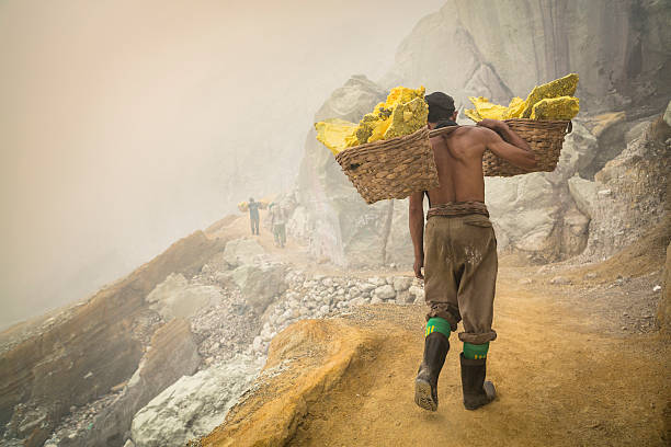 asian trabajador de transporte de cestas de azufre en ijen al volcán - sulfuric fotografías e imágenes de stock