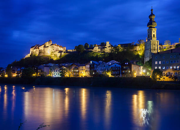 View of Burghausen, Germany Illuminated at Dusk Under Cloudy Sky with View of Burghausen Castle and Church Steeple