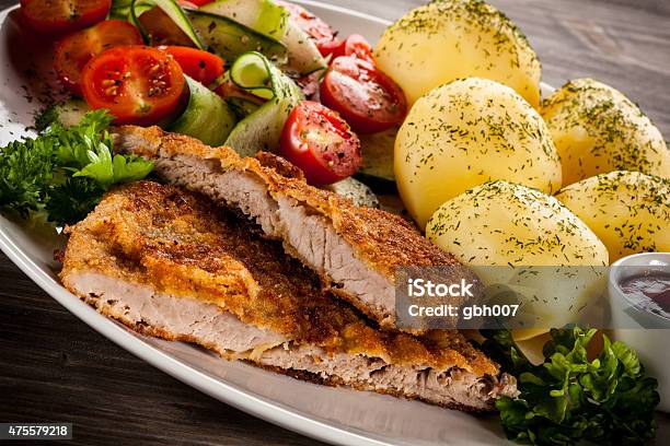 Fried Pork Chops Boiled Potatoes And Vegetables On Wooden Background Stock Photo - Download Image Now