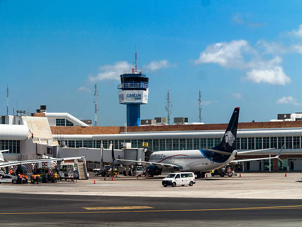 Cancun, Mexico, airport tower and gates Cancun, Mexico - April 24, 2015: The control tower of the international airport of Cancun with an Aero Mexico airplane. cancun stock pictures, royalty-free photos & images
