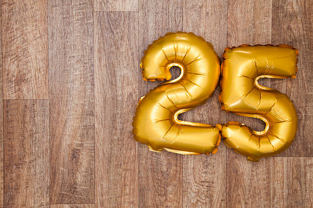 Gold number 25 balloon A gold foil number 25 balloon on a wooden background. The number is made from shiny golden foil and is inflated, it is on the right hand side of the image leaving copy space on the left of the image for your text or logo. 25 29 years stock pictures, royalty-free photos & images