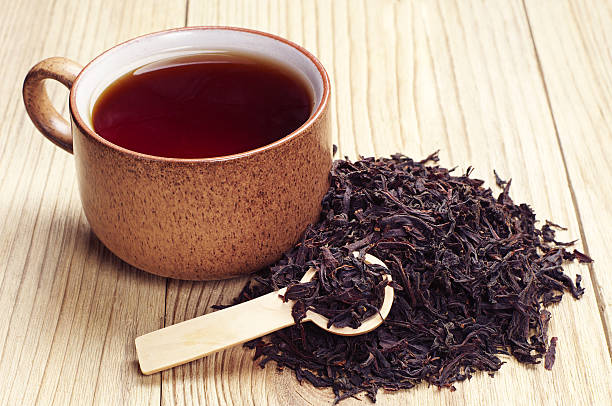 Black tea in a cup Black tea in a cup and dried leaves on wooden background black tea stock pictures, royalty-free photos & images