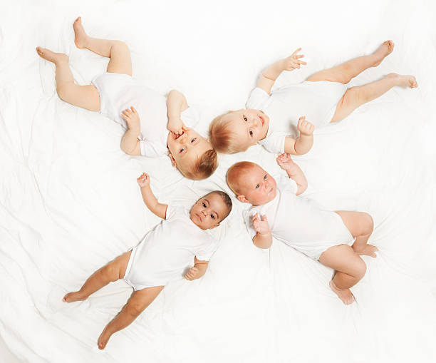 istock Four babies lay in star shape on white background 475618486