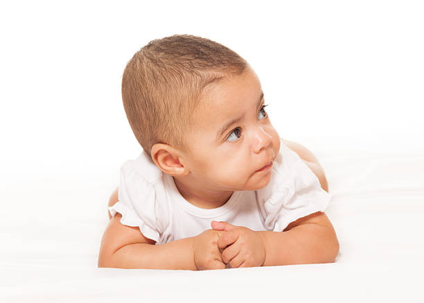 the baby with a cap is lying on the bed and laughing. Blach and white photo