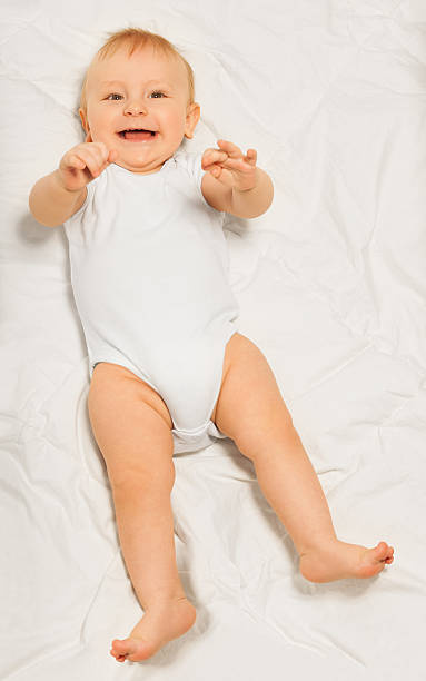 istock Playful small baby wearing white babygro laying 475618666