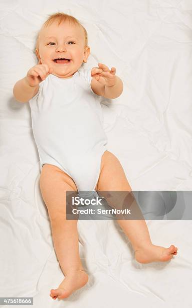 Playful Small Baby Wearing White Babygro Laying Stock Photo - Download Image Now - 2015, Baby - Human Age, Blanket