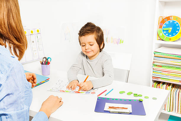 istock Boy colors shapes during ABA with therapist near 475621412