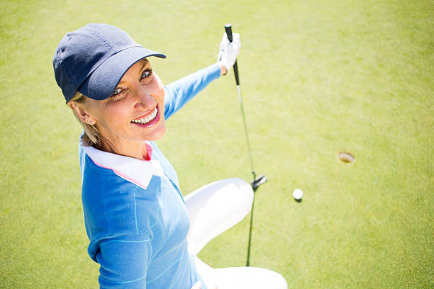 istock Smiling lady golfer kneeling on the putting green 475623672
