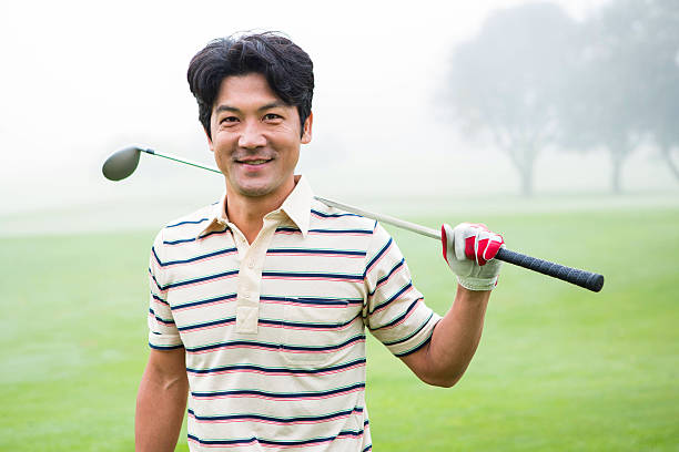 istock Golfer standing and holding his club smiling at camera 475623758