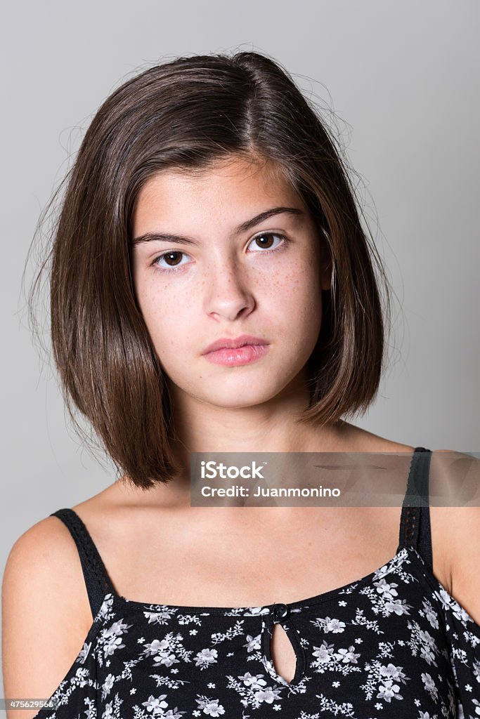 Serious teenage girl Serious teenage girl looking at the camera on gray background 14-15 Years Stock Photo