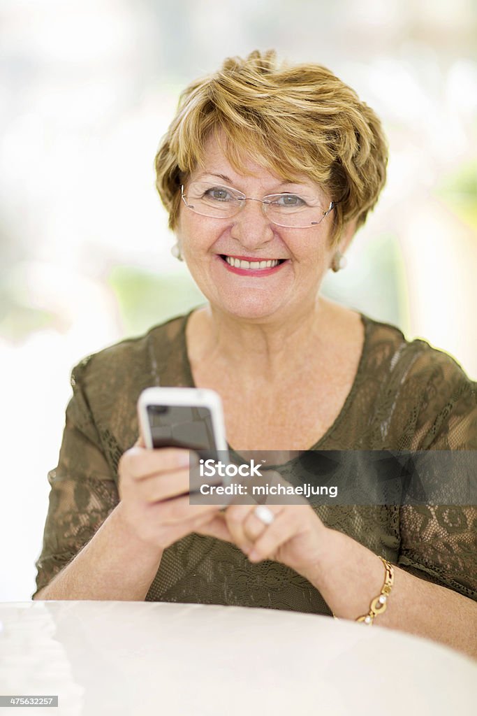 senior woman using smart phone cheerful senior woman using smart phone at home 60-69 Years Stock Photo