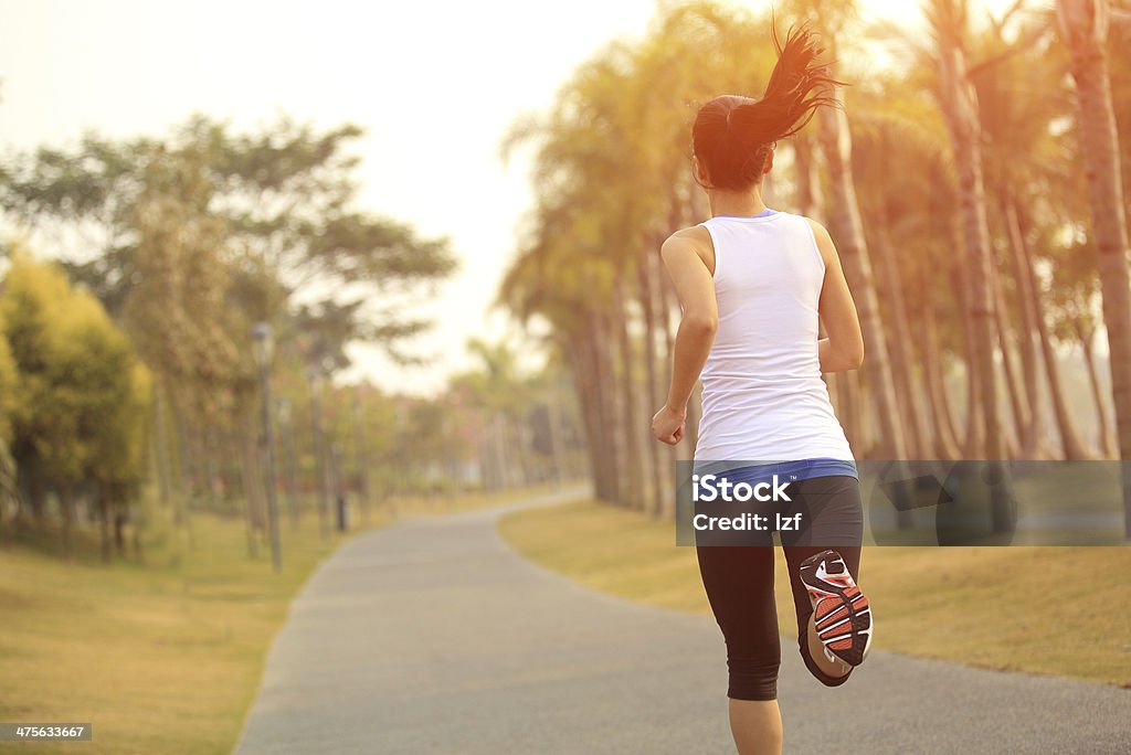 Woman jogging with coconut trees in background healthy lifetyle asian woman jogging  at tropical park Active Lifestyle Stock Photo