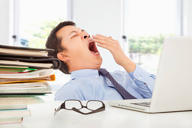 疲れにあくびをする若いビジネスマンの仕事 ストックフォト