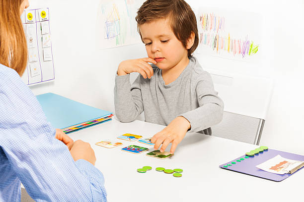 Preschooler boy and developing game with card Preschooler boy plays in developing game at the table with colorful matching cards with his parent indoors autism photos stock pictures, royalty-free photos & images