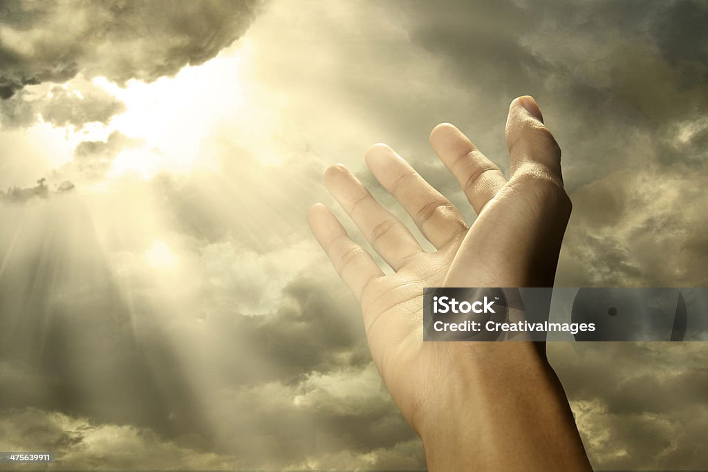 Hand reaching toward the sky Hand reaching for a ray of light on the sky Heaven Stock Photo