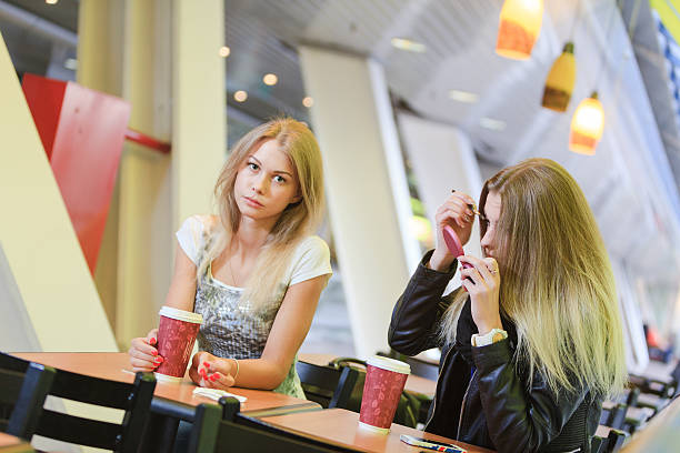 istock Two young girls drinking coffe and doing makeup in cafe. 475643132
