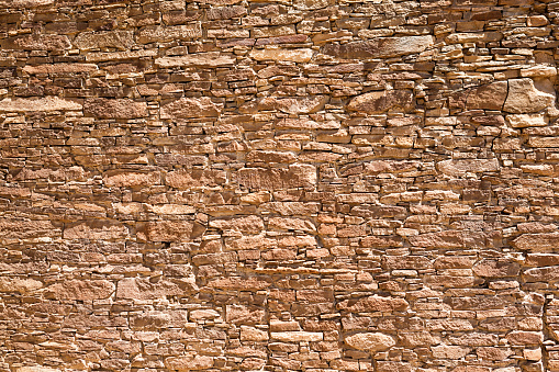 An exterior wall of the historic adobe building in Chaco Culture National Historical Park in New Mexico, USA. The Chaco Culture National Historical Park with its ancient Pueblo adobe dwelling historic ruins is a favorite tourist destination in New Mexico, USA. The rock and adobe wall were photographed on location in the National Park.