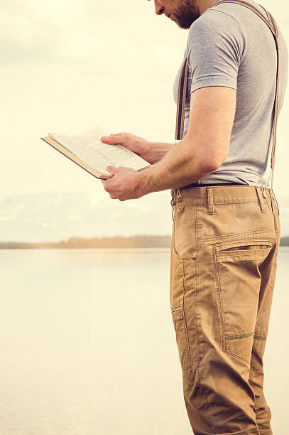 istock Young Man reading book outdoor 475654458