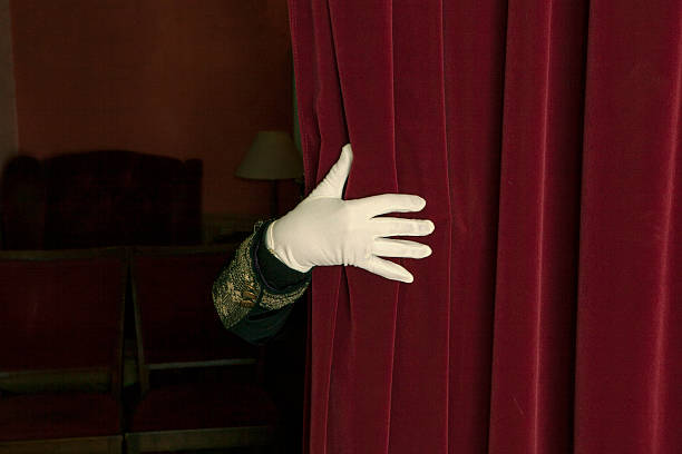 istock Hand in white gloves unveil the curtain. 475657697