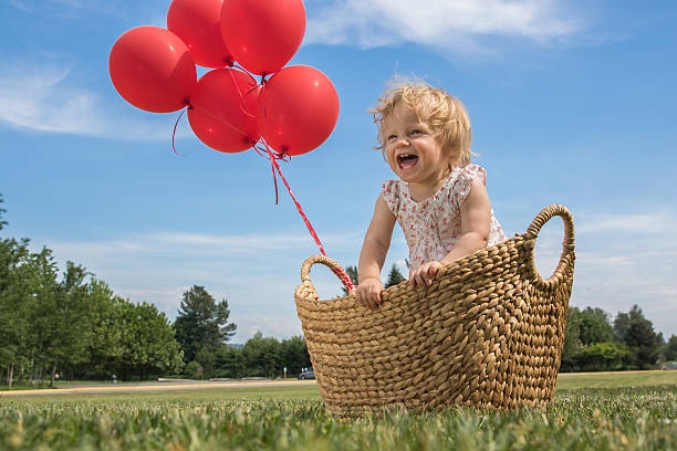 ベビーガールのバスケットにレッドの風船 - balloon moving up child flying ストックフォトと画像