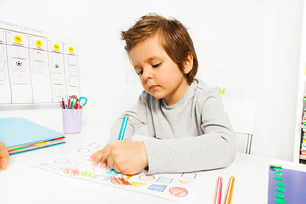 istock Small boy draws with pencil on the paper sitting 475663892