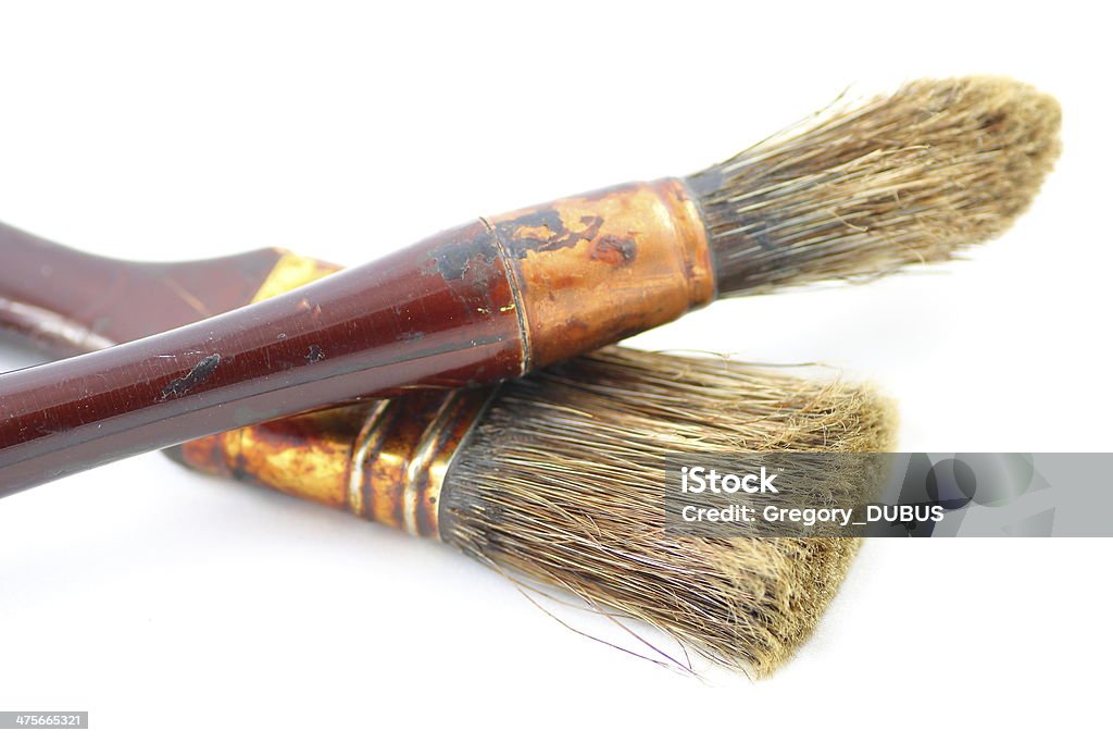 Brown paintbrushes on white Two superposed dry paintbrushes isolated on white background. They were used repeatedly to make the stain wood, this is what gives this brown color on metal and bristles. Focus on brush bristles. Art Stock Photo