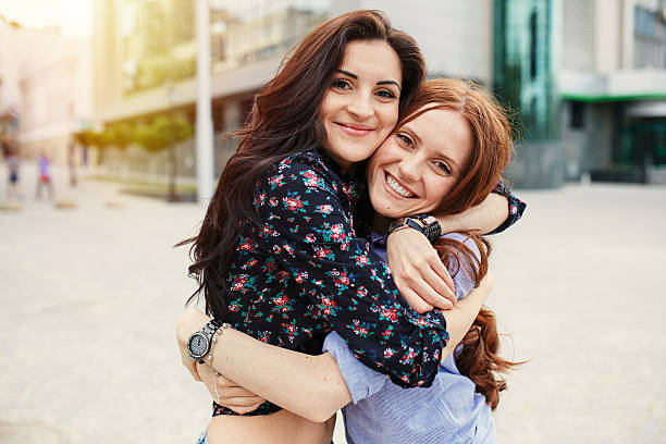 Two cheerful sisters hugging stock photo