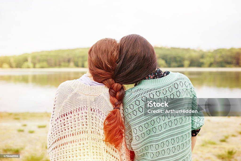 Two sisters with interwoven hairs Two sisters with interwoven hairs looking at the lake. Light leak effect 2015 Stock Photo